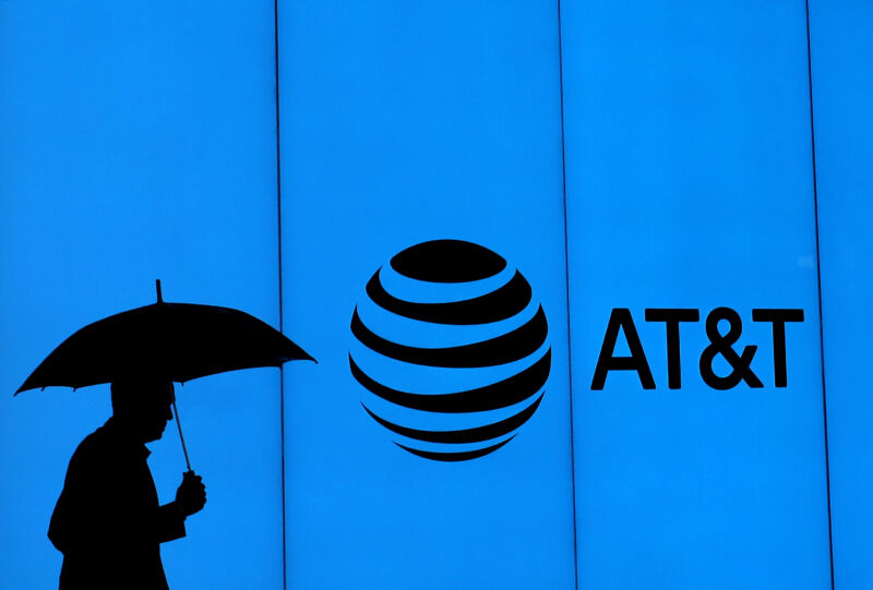 Image 1: A man with an umbrella walking past a building with an AT&T logo.