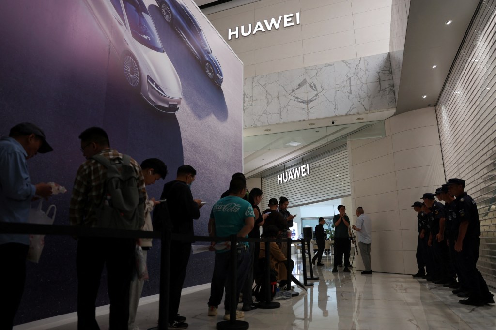 图片 1：周五，人们在北京华为旗舰店外排队。