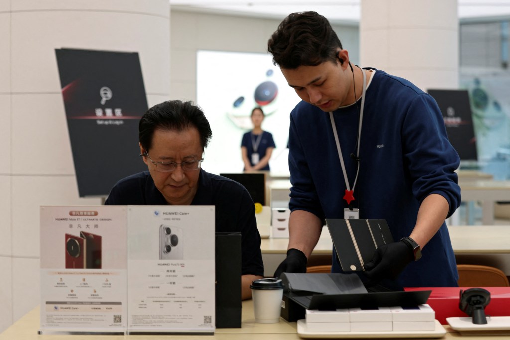 图片 4：一名工作人员帮助顾客使用华为 Mate XT