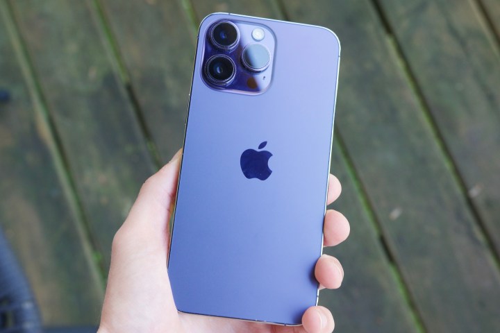有人手持深紫色 iPhone 14 Pro Max，展示手机背面。
