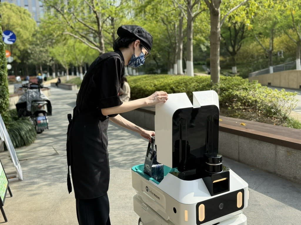 上海的一名工人将外卖订单放入 Infermove Carri LITE 机器人中，这是该市日益采用自主配送技术的一部分。（照片：Infermove）
